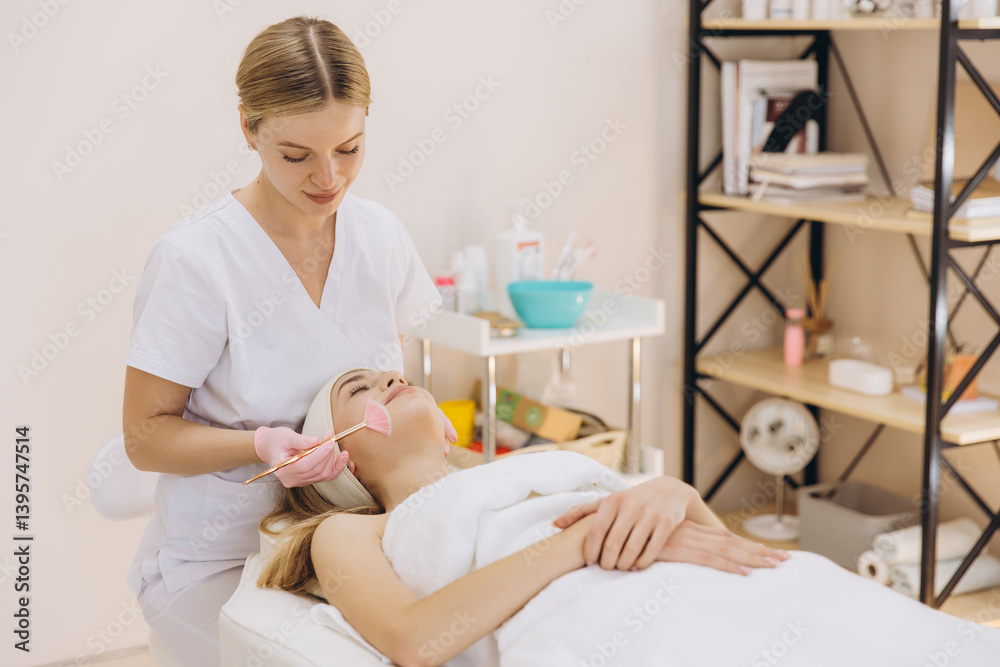Obraz premium Makeup artist brushing foundation onto client's skin during professional beauty treatment in calm, bright spa environment
