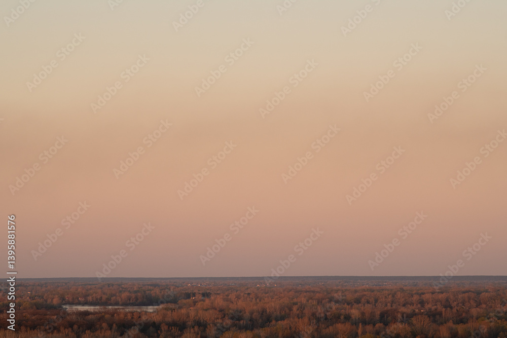 Fototapeta premium This breathtaking view captures the horizon as the sun sets, illuminating the vast landscape filled with autumn colors. The peaceful scene showcases nature's beauty at dusk