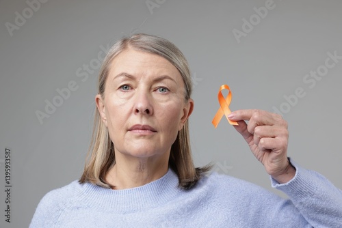 Multiple Sclerosis awareness. Woman with orange ribbon on light grey background