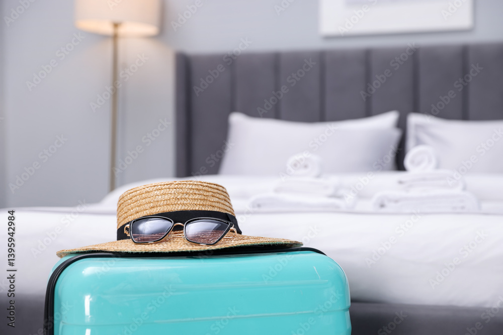 Fototapeta premium Suitcase with hat and sunglasses in hotel room, closeup