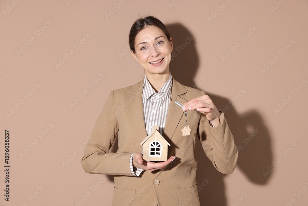Real estate agent holding key with keychain and house model on beige background Real estate agent holding key with keychain and house model on beige background