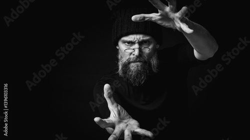 Black and white, dramatic portrait of an energetic man with a beard and glasses, reaching towards the camera. Subtle lighting, emotional expression, dark background, mysterious concept