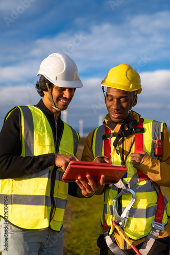 Obraz na płótnie Two engineers smiling and using digital tablet in a wind turbine farm w salonie
