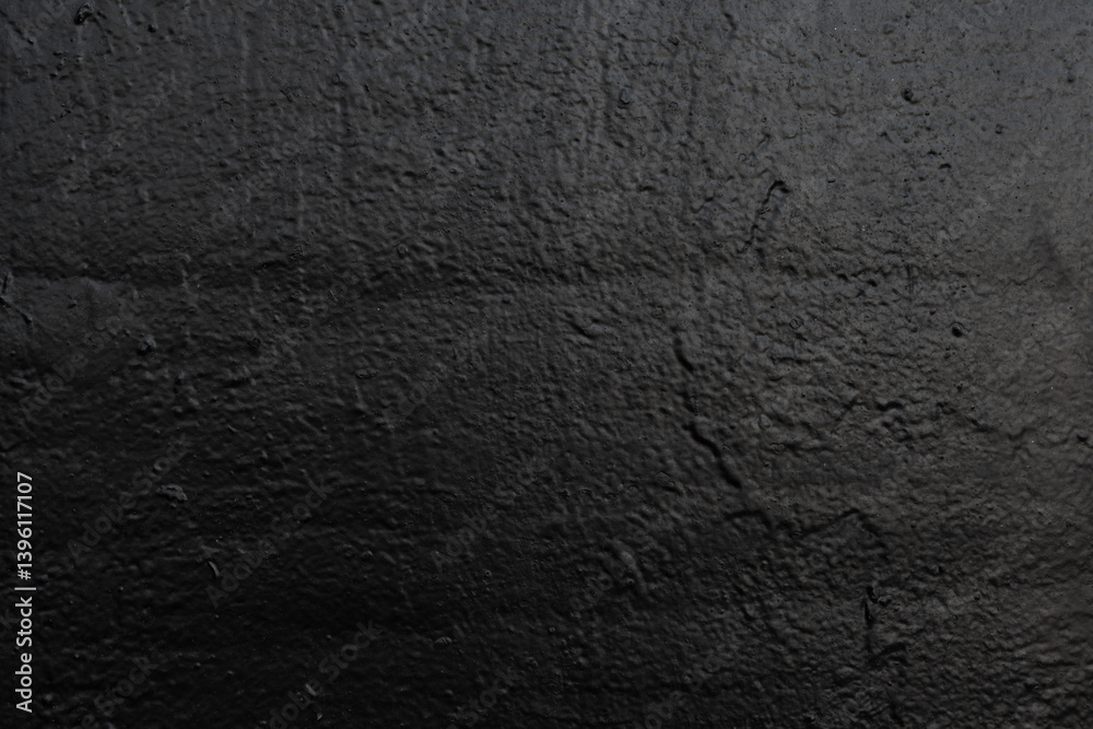 Dark textured surface with a rough appearance. Concrete wall