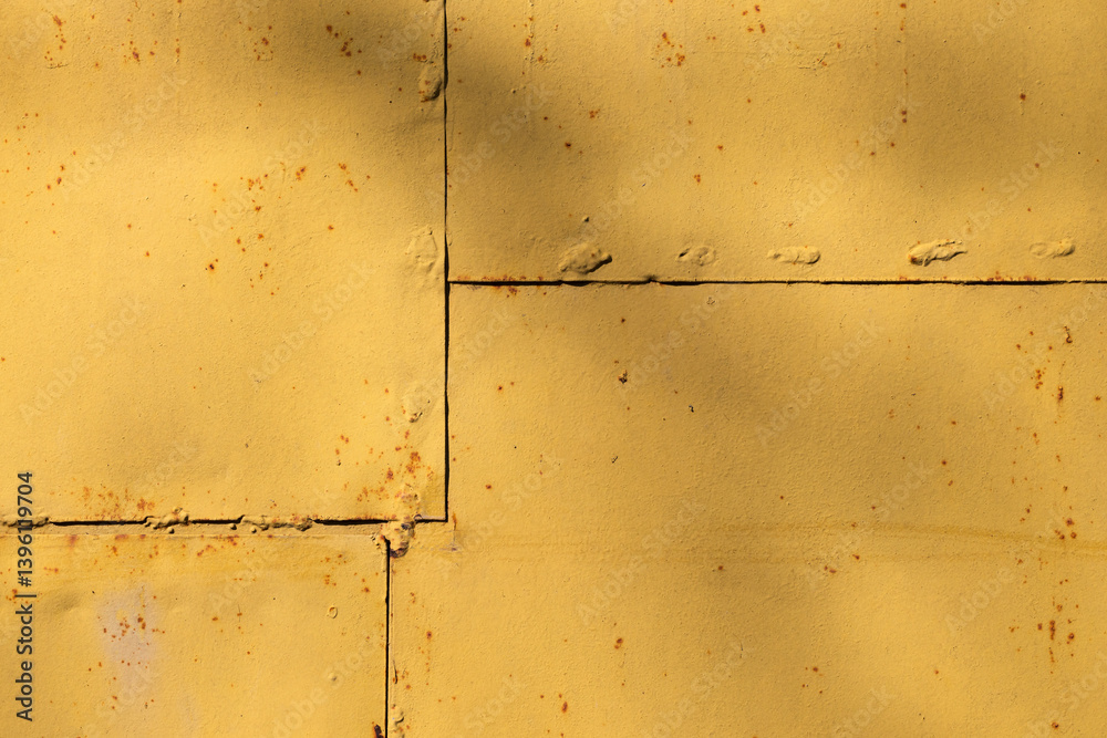 Yellow painted metal panels with rust and welding seams, industrial texture