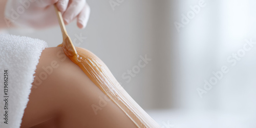 Sugar waxing. The cosmetologist applies sugaring paste to the female's leg.