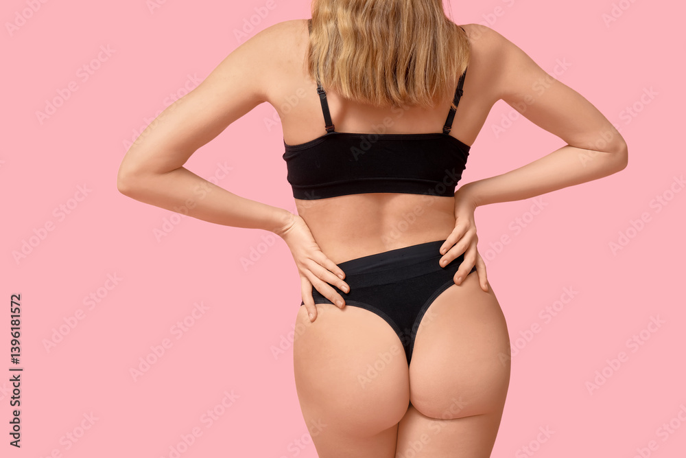 Fototapeta premium Pretty young woman in black cotton underwear on pink background, back view