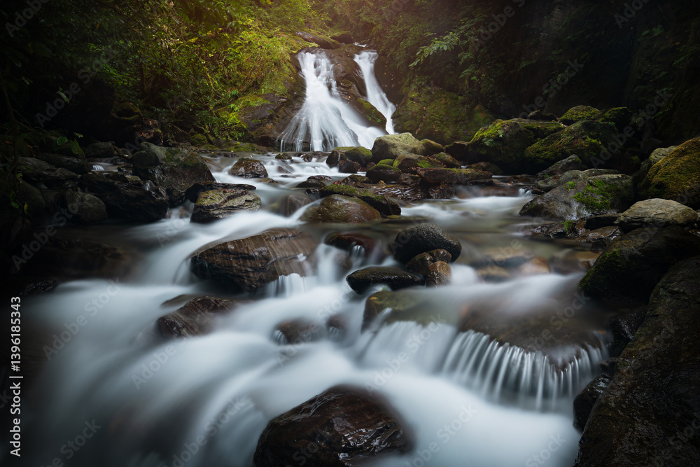 Stunning waterfall in Adjara, Georgia, flowing over moss-covered rocks in a lush green forest. The long exposure effect creates a smooth, silky look to the water.