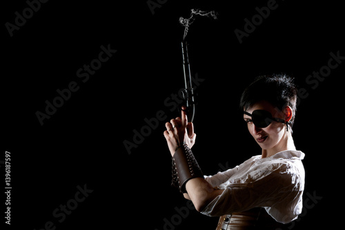 Woman pirate girl with ancient smoking pistol in hands, short hair and eye patch on a black background. Dramatic light.