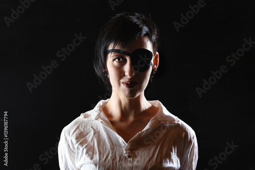 Obraz na płótnie Woman pirate girl with short hair and eye patch in white shirt on a black background. Dramatic light. w salonie