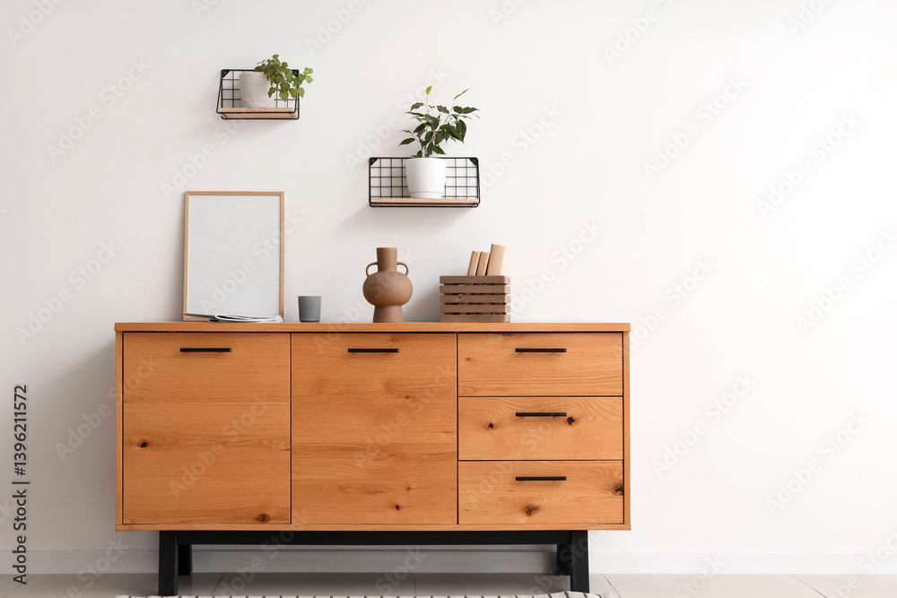 Chest of drawers, picture frame and shelves with houseplants on white wall in living room Chest of drawers, picture frame and shelves with houseplants on white wall in living room