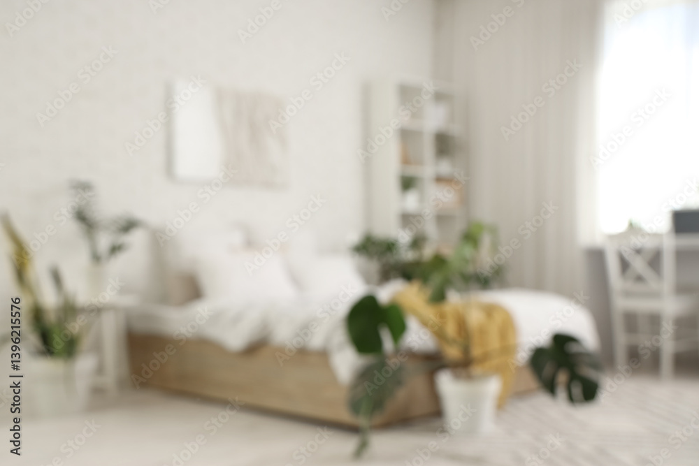 Fototapeta premium Blurred view of light bedroom with green plants and shelf unit