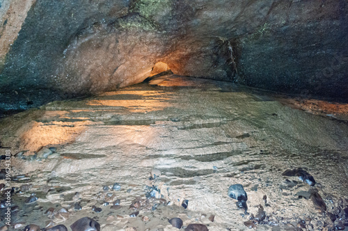 A cave with a sandy floor and rocks scattered around