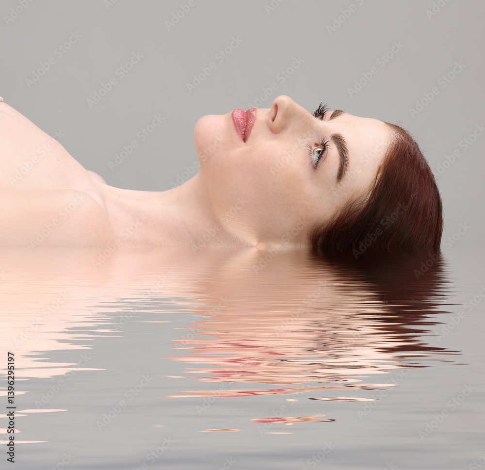 Beautiful woman in water on grey background Beautiful woman in water on grey background