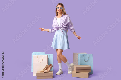 Obraz na płótnie Stylish young woman with shopping bags and shoe boxes on lilac background w salonie