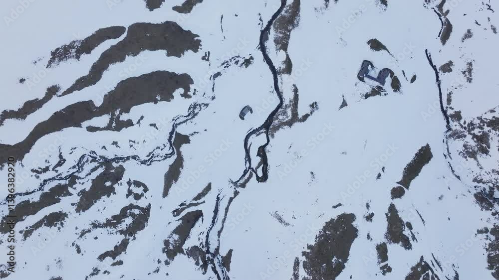 Aerial shot - Aerial drone footage revealing snow covered mountain terrain at Pyrenees National Park, traversing Spanish French border with winding river cutting through pristine wilderness landscape