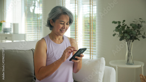 Asia adult people middle age happy relax old woman using mobile ask AI chatGPT chat bot look health care app sit at home sofa elder aging asian aged female. Online social media smart pay order system.