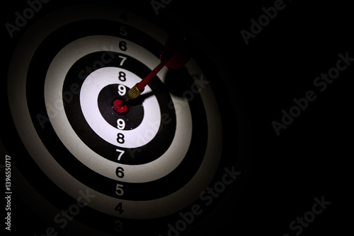 Dart arrow hitting in the target center of dartboard,Arrow on a black background