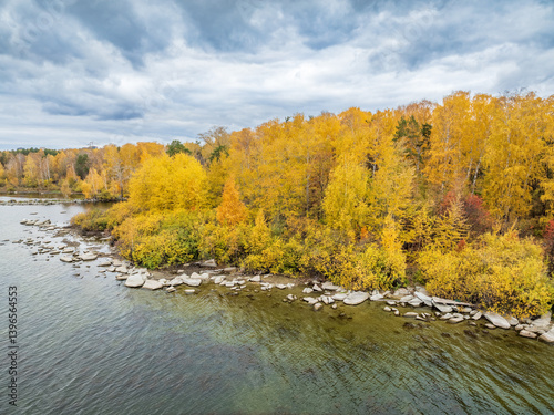 Colorful autumn forest with trees on the shore of a blue lake - top aerial view.