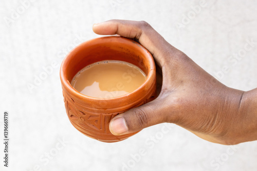 Canvastavla A female hand holds hot milk tea, or dudh cha, in a traditional clay cup