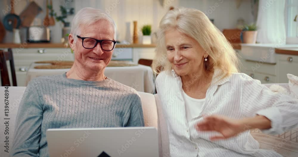 Grandparents calling by video conference to relatives, using laptop at home. Distant communication, modern technology for connecting people, happy old man and woman smiling to camera and waving hands Grandparents calling by video conference to relatives, using laptop at home. Distant communication, modern technology for connecting people, happy old man and woman smiling to camera and waving hands