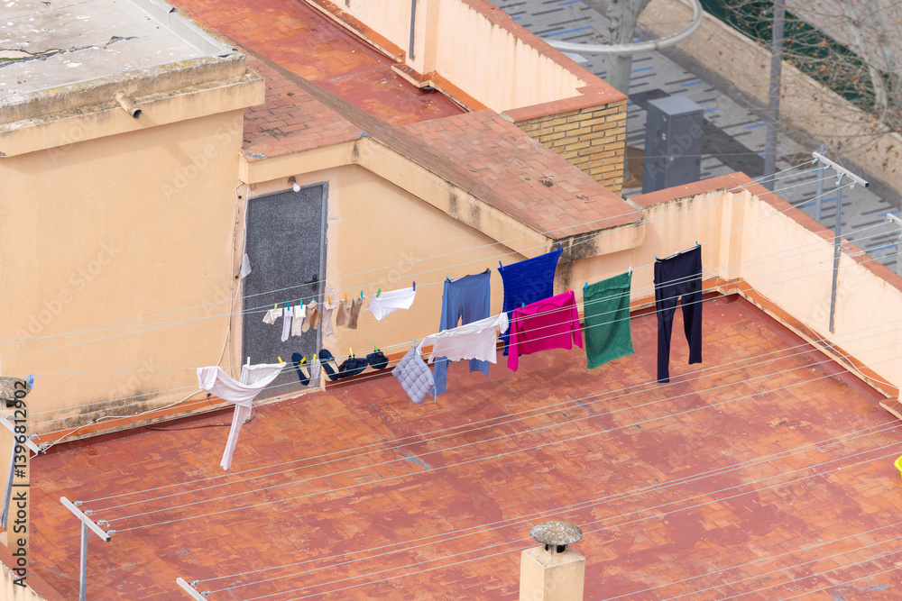 Photo of clean clothes drying and pegged on a washing line on top of a Spanish apartment block showing the laundry drying on top of the high rise building with the wind blowing the clothes