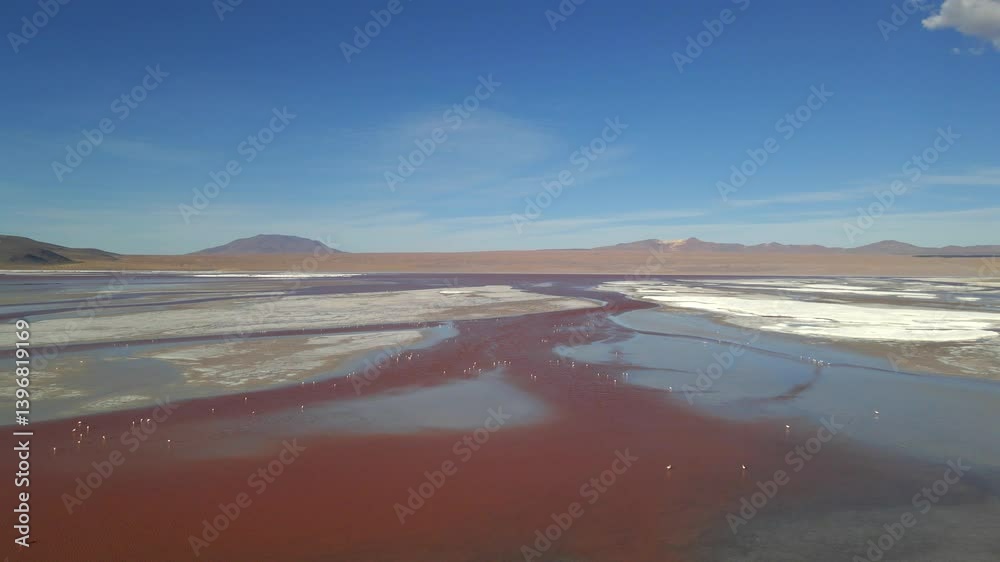 Drone flight over full Laguna Colorada expanse with red hues and surrounding crater formations Drone flight over full Laguna Colorada expanse with red hues and surrounding crater formations