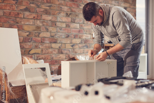 Obraz na płótnie Man working and assembling furniture in a new apartment. w salonie