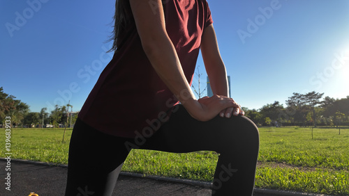 Obraz na płótnie Young woman stretching after exercise and jogging in urban park during sunny summertime day.. w salonie