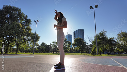 Obraz na płótnie Young exhausted woman drinking water after jogging and exercise in urban park.. w salonie