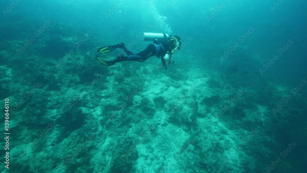 Diver swims above seabed recording video with action camera Diver swims above seabed recording video with action camera