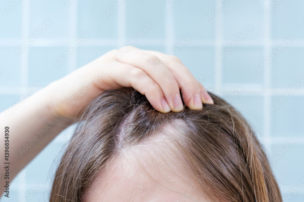 Naklejka premium Woman touching her hair close-up against background of blue tiles, hair loss concept.