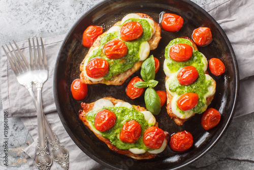 Obraz na płótnie Chicken margherita is made with juicy pan-seared chicken, topped with basil pesto, mozzarella, roasted cherry tomatoes close-up on pan on table. Horizontal top view from above w salonie