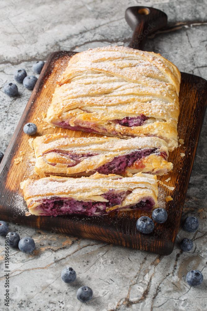 Puff pastry pie with blueberries and cream cheese close-up on wooden board on table. Vertical
