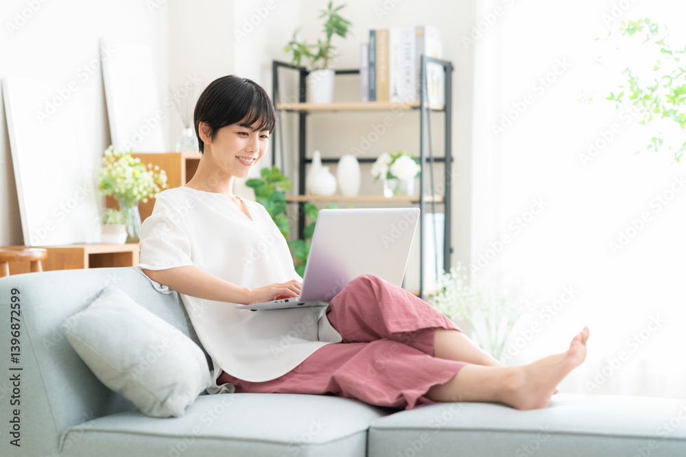 リビングでパソコンを使う若い女性 リビングでパソコンを使う若い女性