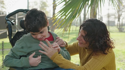 Loving mother interacting with disabled son in wheelchair photo