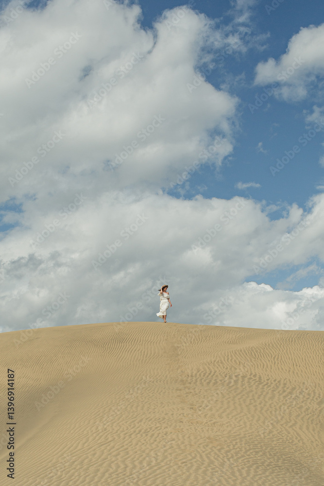 Obraz premium Person Walking on Sandy Dune Under Blue Sky