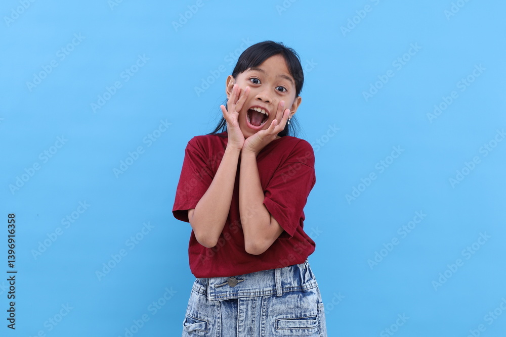 Adorable asian girl standing while shouting with hand near mouth. Isolated on blue background Adorable asian girl standing while shouting with hand near mouth. Isolated on blue background