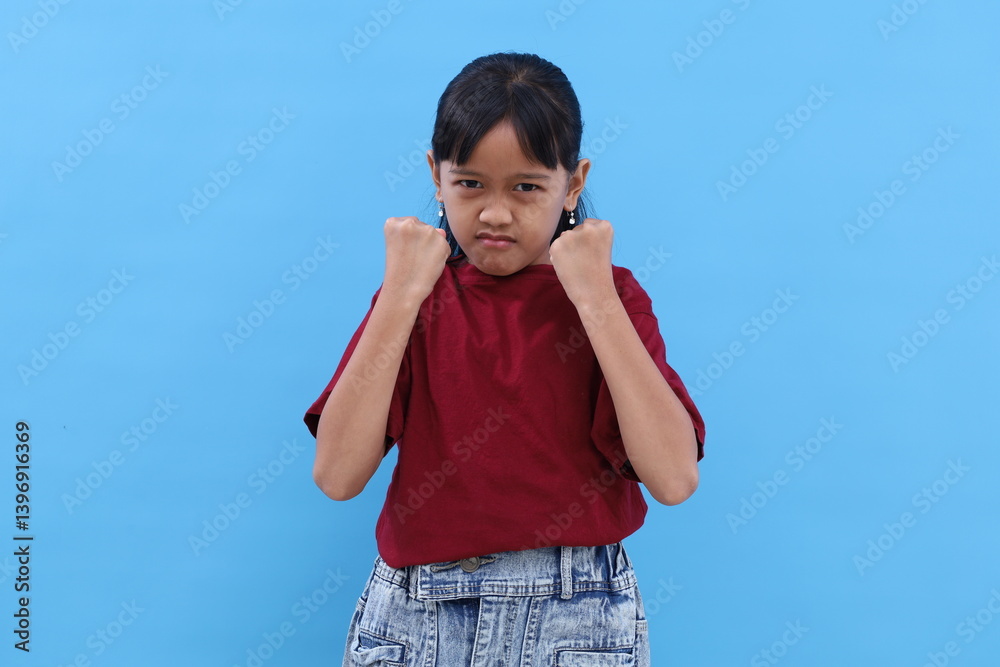 Angry little asian kid showing frustration and disagreement. Isolated on blue background Angry little asian kid showing frustration and disagreement. Isolated on blue background