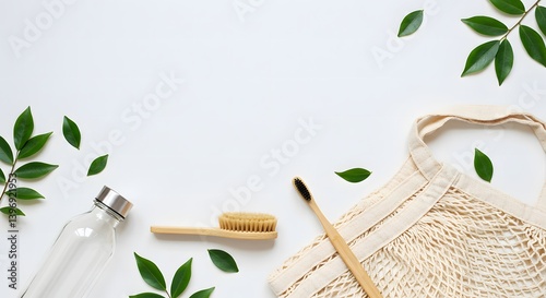 Eco-friendly items like a glass bottle, bamboo toothbrush, natural scrub brush, and reusable cotton bag arranged with green leaves on a white background.
