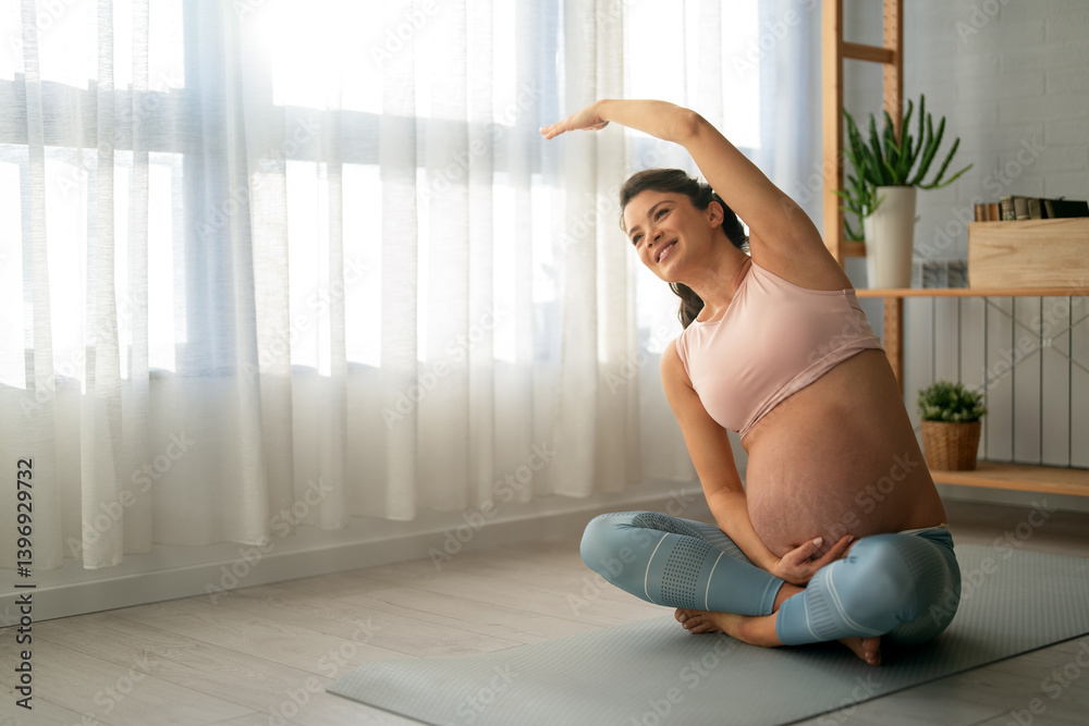 Portrait of young pregnant female working out at home. Pregnant woman practicing yoga at home.