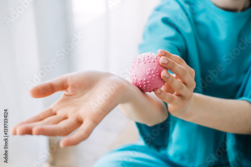 Close-up of woman applying a pink massage ball to her forearm. Tactile wellness, sensory therapy, mindful touch, daily stress relief