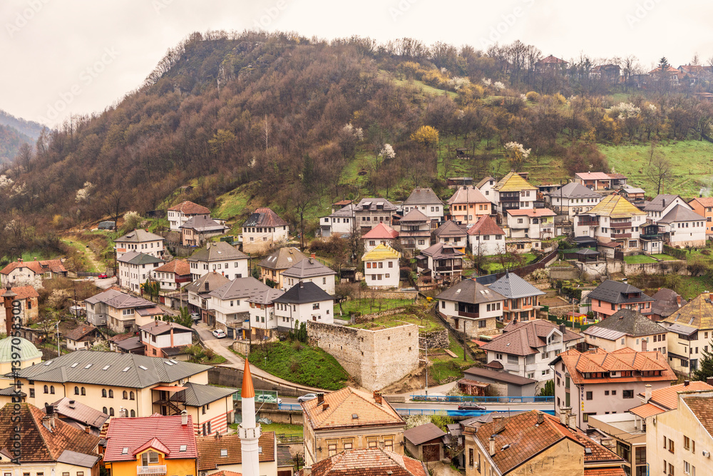 Fototapeta premium Panoramic view of the old residential area in Travnik, Bosnia and Herzegovina, with traditional houses on a hillside and spring greenery. Photographed on March 25, 2025.