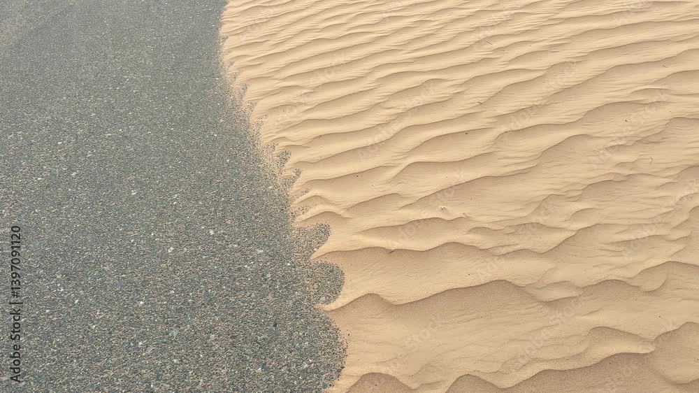 Strong wind blows across desert dune, shaping its curves and shifting sand particles. Powerful gusts lift fine grains, forming a dynamic landscape with ever-changing dune patterns in the vast terrain