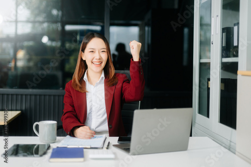 Young Asian businesswoman working with working notepad, tablet and laptop documents talking on the smartphone, tablet