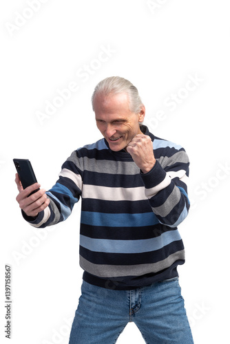 Excited senior man celebrating success on smartphone, raising fist in triumph