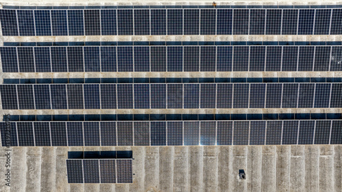 Aerial perpendicular view of rows of solar panels installed on the roof of a building. Clean energy concept.