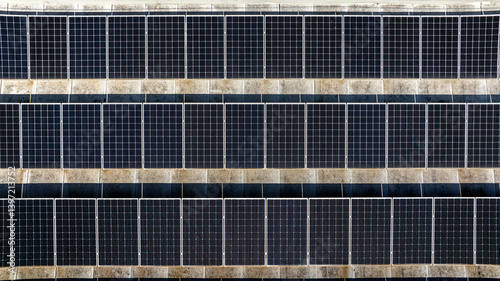 Aerial perpendicular view of rows of solar panels installed on the roof of a building. Clean energy concept.