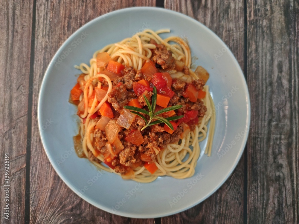 Spaghetti ground beef sauce served in a plate on wooden table.