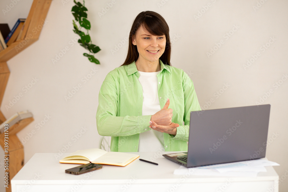 Young deaf woman actively participating in a virtual online conference with her employees. Woman is talking on a video call, using sign language and showing gestures to communicate effectively. Young deaf woman actively participating in a virtual online conference with her employees. Woman is talking on a video call, using sign language and showing gestures to communicate effectively.